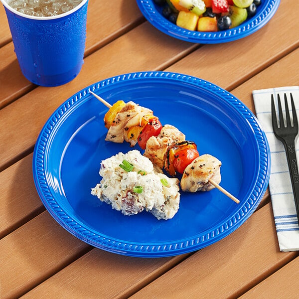 A blue plastic plate with food, a fork, and a drink on a table.