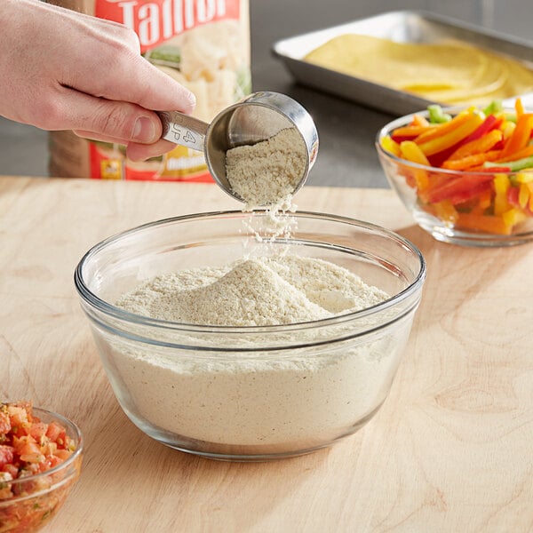 A person pouring Maseca Tamal corn masa flour into a bowl.