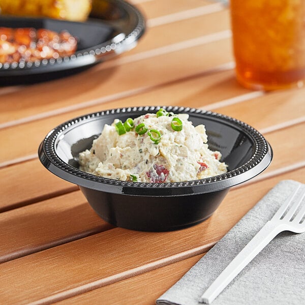 A close up of a black plastic bowl filled with food on a table