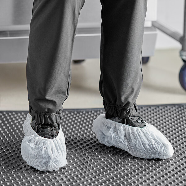 A person wearing white shoes with Choice white polypropylene shoe covers.