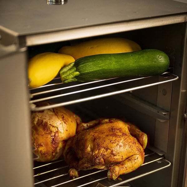 A chicken and zucchini cooking in a SmokinTex electric smoker with vegetables.