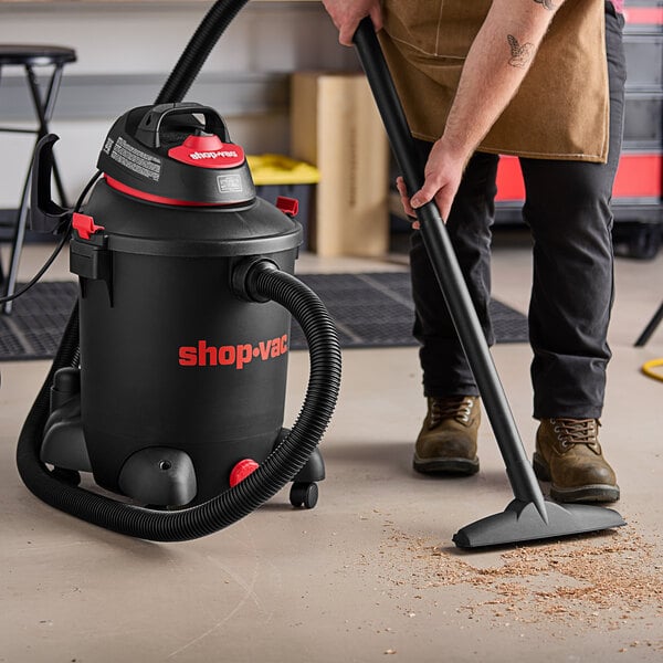 A man using a Shop-Vac wet/dry utility vacuum to clean a floor.