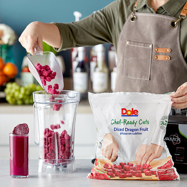 A woman pouring Dole Chef-Ready Cuts IQF Diced Pitaya Dragon Fruit into a blender.