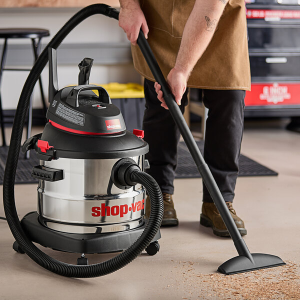 A man using a Shop-Vac wet/dry vacuum to clean a floor.