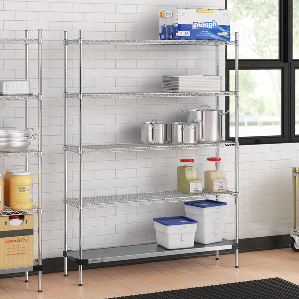 A Regency chrome wire shelving unit in a professional kitchen with food containers and pots on the shelves.