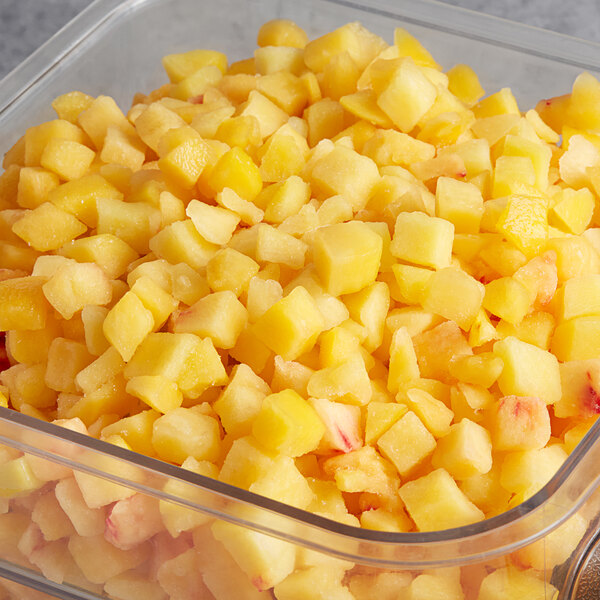 A clear container filled with Dole Chef-Ready Cuts IQF diced peaches.