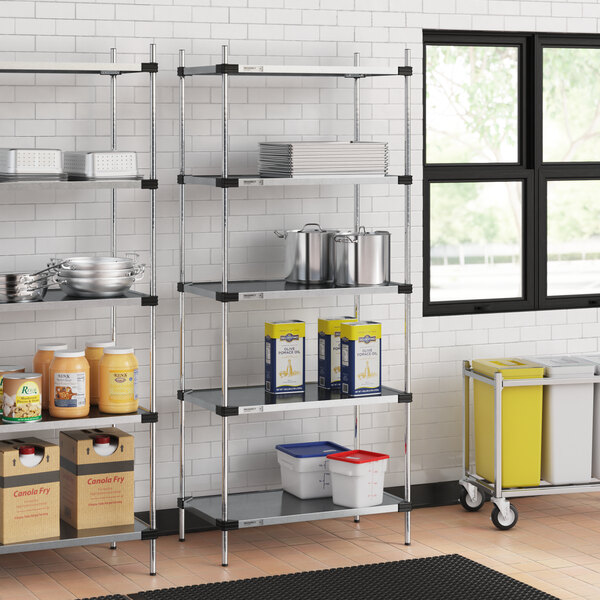 Regency galvanized steel shelves in a school kitchen with food containers on them.