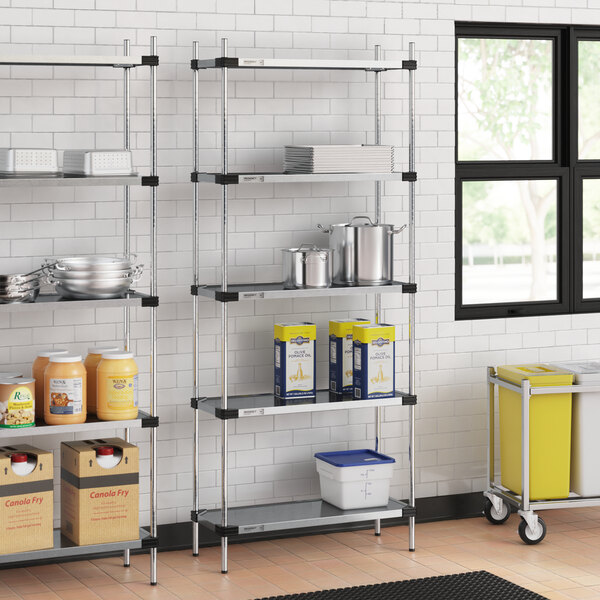 Regency galvanized steel shelves holding food containers in a school kitchen.