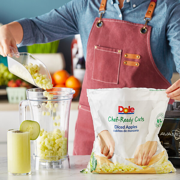 A person pouring Dole Chef-Ready Cuts IQF Diced Apples into a blender.