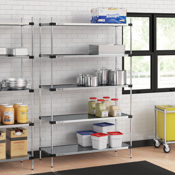 Regency galvanized steel shelves in a professional kitchen with white and blue plastic containers and a white bucket with a red lid.