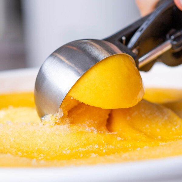 A metal scoop with yellow Pitaya Foods Organic Passion Fruit Sorbet.