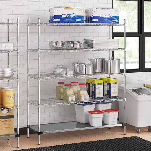 A Regency metal wire shelving unit in a school kitchen filled with food containers and pots.