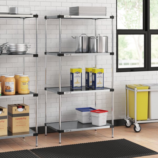 A four-shelf galvanized steel shelving unit with 74-inch posts, used for storage in a commercial kitchen or pantry.