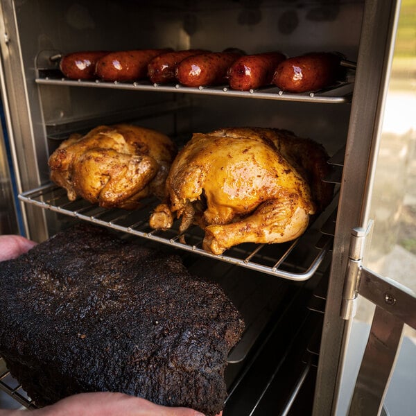 A person using the SmokinTex 1400 Pro Series Electric Smoker to cook meat on a rack.