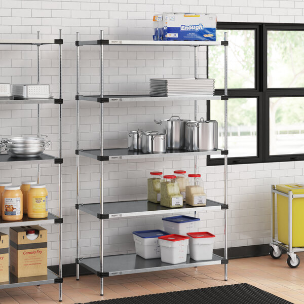 A Regency galvanized steel shelf kit in a professional kitchen with food containers on the shelves.