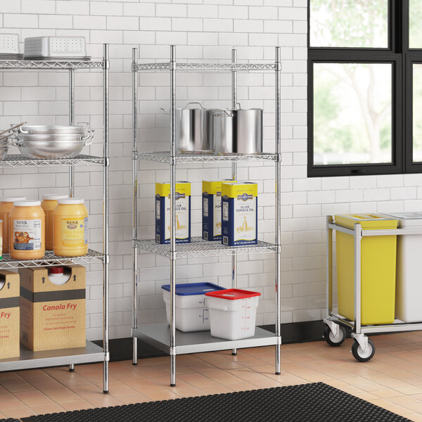 Stainless steel wire shelves with food containers on a solid stainless steel shelf.