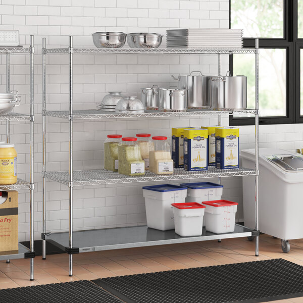 A metal Regency wire shelving unit in a professional kitchen with food containers on it.