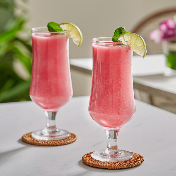 Two glasses of pink Oregon Fruit Prickly Pear drink with lime slices.