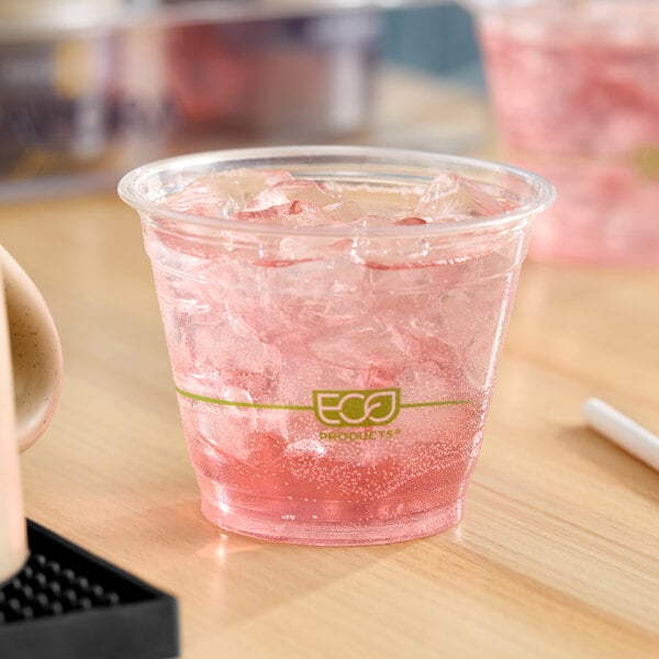 A clear compostable plastic cup filled with a pink iced beverage.