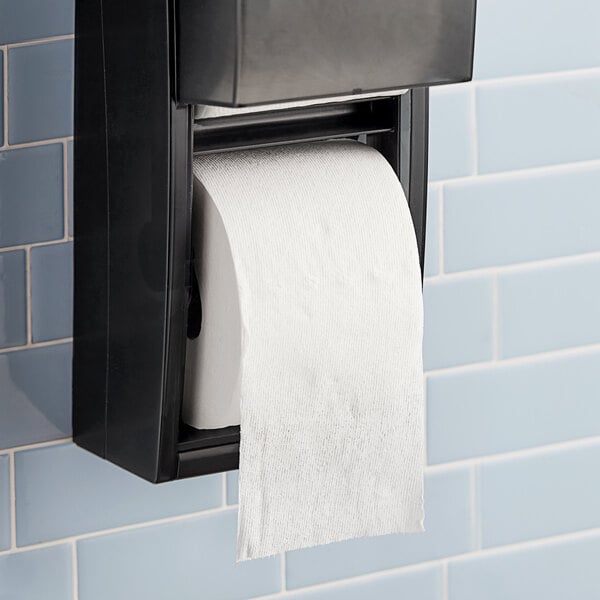 A Charmin Essentials Mega Roll of 2-ply toilet paper on a black toilet paper holder.