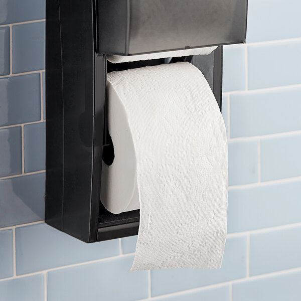 A Charmin Essentials Mega Roll of 2-ply toilet paper on a black toilet paper holder.