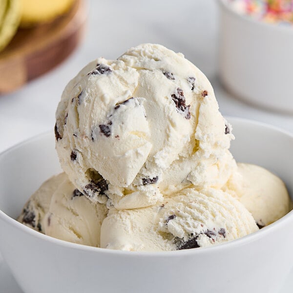 A close-up of a bowl of Tillamook Mint Chocolate Chip ice cream with chocolate chips and a banana.