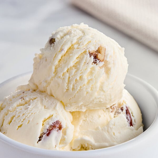 A close up of a bowl of Tillamook Butter Pecan ice cream with a scoop on top.