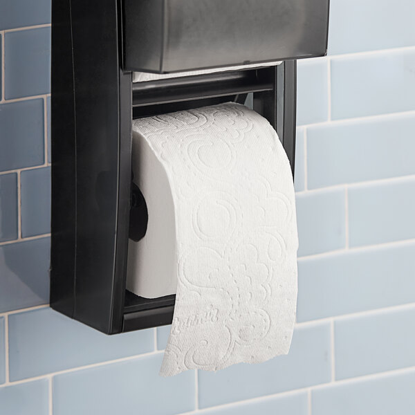 A white toilet paper roll on a black dispenser.