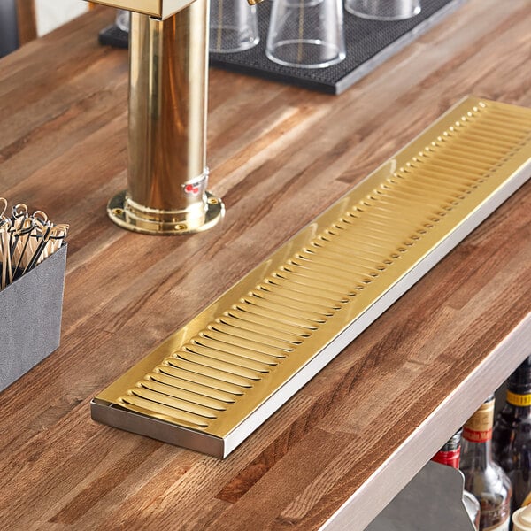 A Regency PVD gold surface-mount beer drip tray on a bar counter.