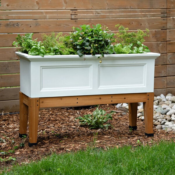 A white Mayne Fairfield planter box with plants in it.