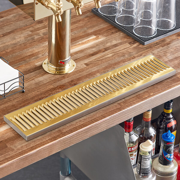 A Regency PVD gold surface-mount beer drip tray on a bar counter.