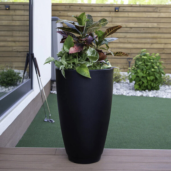 A black Mayne Caprio planter with a plant on a table.