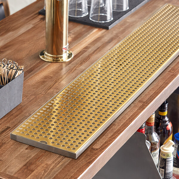 A Regency gold metal surface-mount beer drip tray on a bar counter.