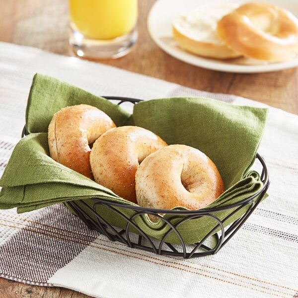 Whole wheat mini bagels in a basket on a table.