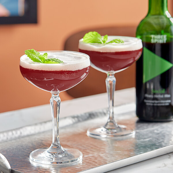 A table with a bottle of Three Spirit Social Elixir and two glasses of red liquid.