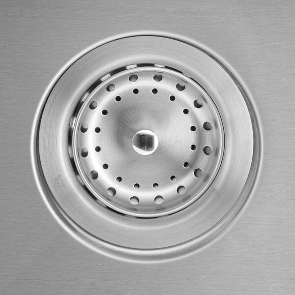 A close-up of the drain on an American Standard stainless steel sink with two compartments.