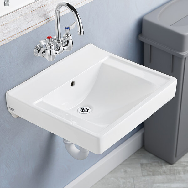 An American Standard white wall-mount lavatory sink with a drain.