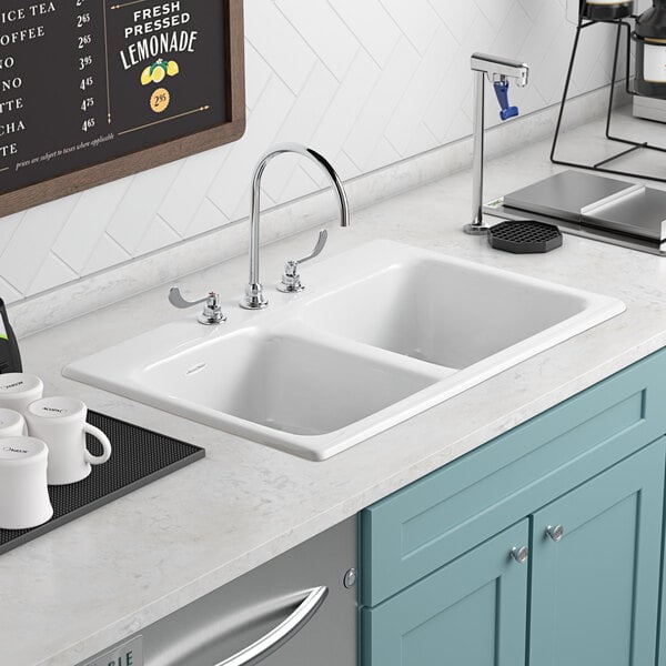 A white American Standard Quince sink with silver faucets over a metal surface.