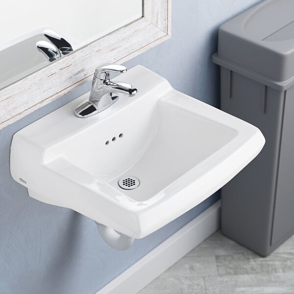A white American Standard wall-mount lavatory sink with a silver faucet.