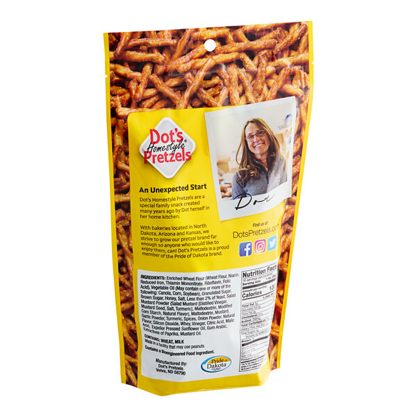 A woman holding a bag of Dot's Homestyle Honey Mustard Seasoned Pretzel Twists.