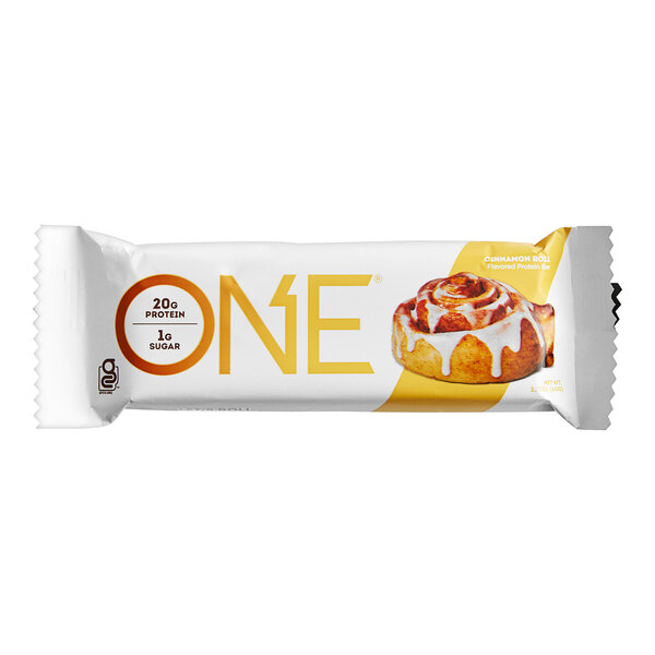 A ONE Cinnamon Roll protein bar in white packaging with yellow text.