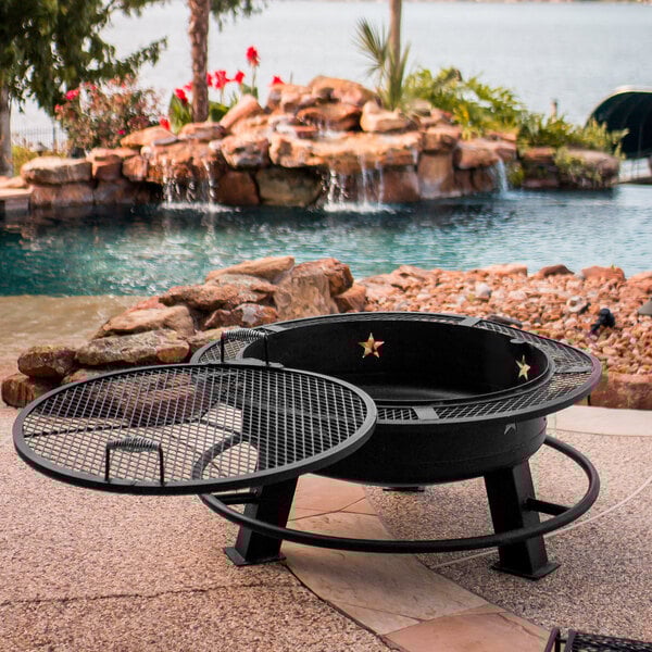 A round black Old Country BBQ Pits fire pit with a grill over the top.