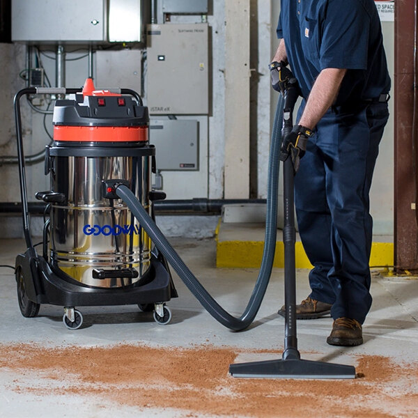 A man using a Goodway Twin-Motor Wet/Dry Vacuum to clean a dirt floor.