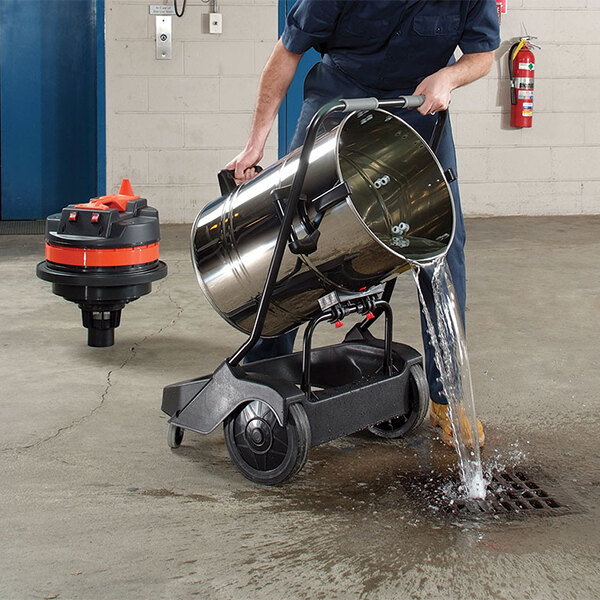 A man using a Goodway Twin-Motor Wet / Dry Tilt Vacuum to clean up water in a metal container.