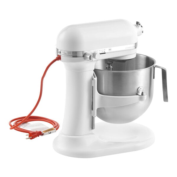 A white KitchenAid countertop mixer with standard accessories and a red cord.