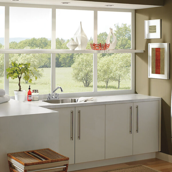 A Delta deck-mount laundry faucet with chrome finish and blade handles above a sink under a window.