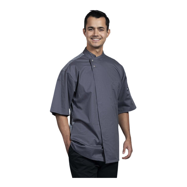 A man wearing a Uncommon Chef slate grey short sleeve chef coat with a grey mesh back.