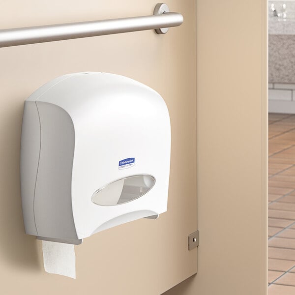 A white Kimberly-Clark Professional jumbo roll horizontal toilet paper dispenser on a wall.