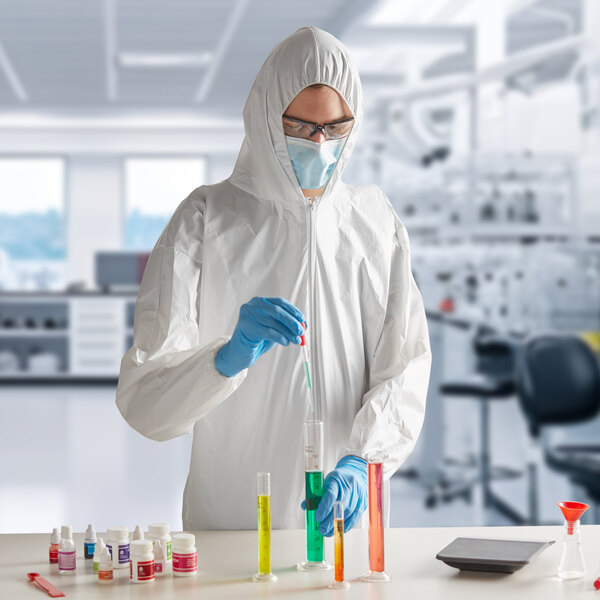 A man in a Lavex white protective suit and mask holding a test tube.
