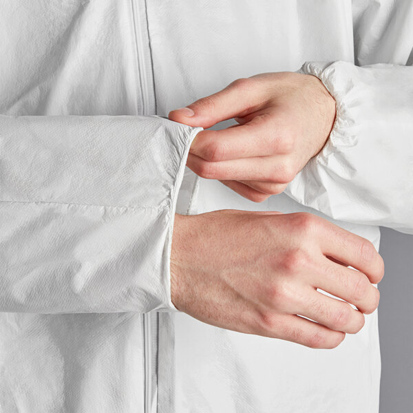 A person wearing a Lavex white microporous coverall is adjusting their sleeves.